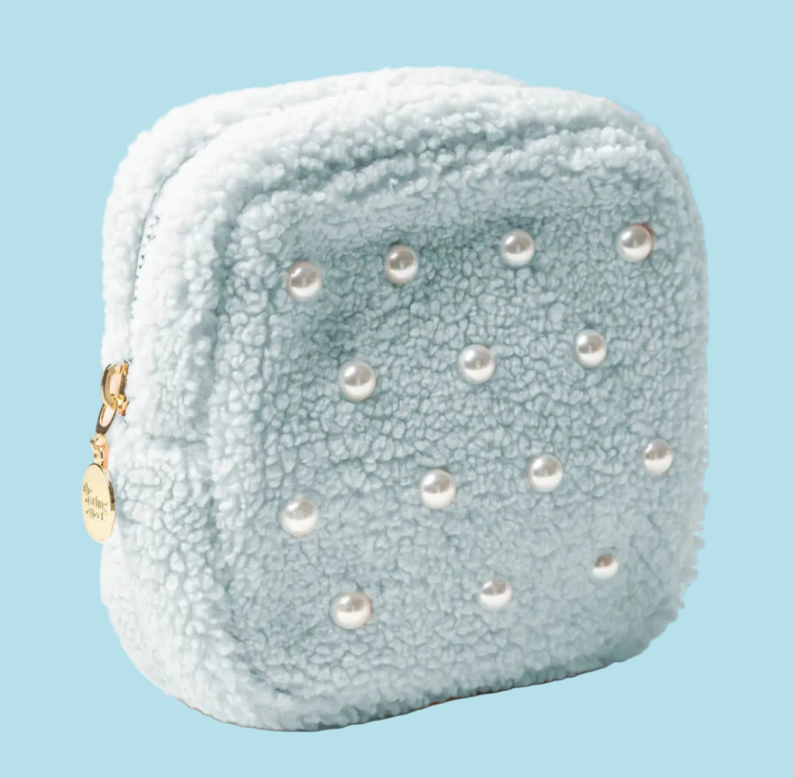 Light blue textured pouch with pearl-like embellishments on a beige background