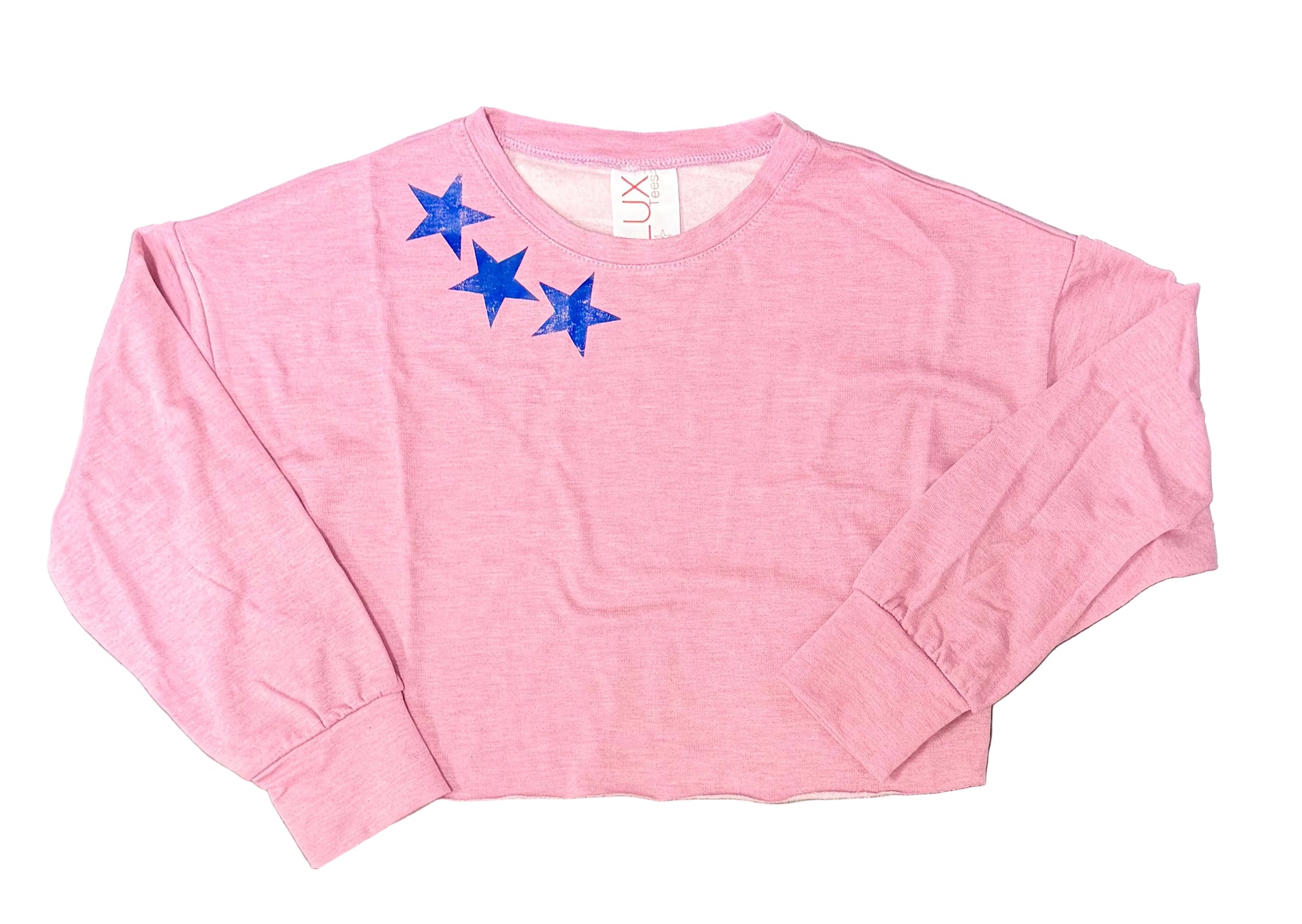 A pink long-sleeve cropped sweatshirt with three blue embroidered stars on the left chest, laid flat on a dark gray tiled surface.