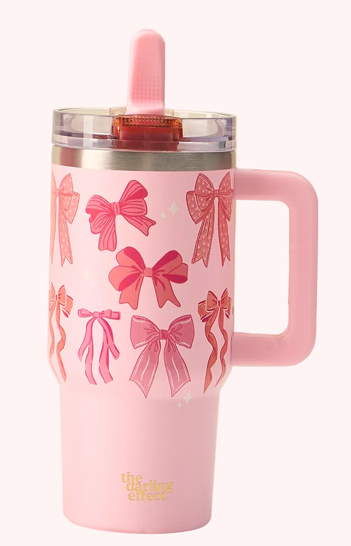 Pink tumbler with bow pattern and handle on a light background