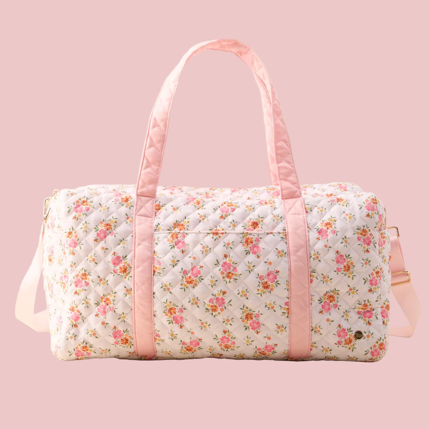 Floral patterned duffel bag with pink accents on a beige background
