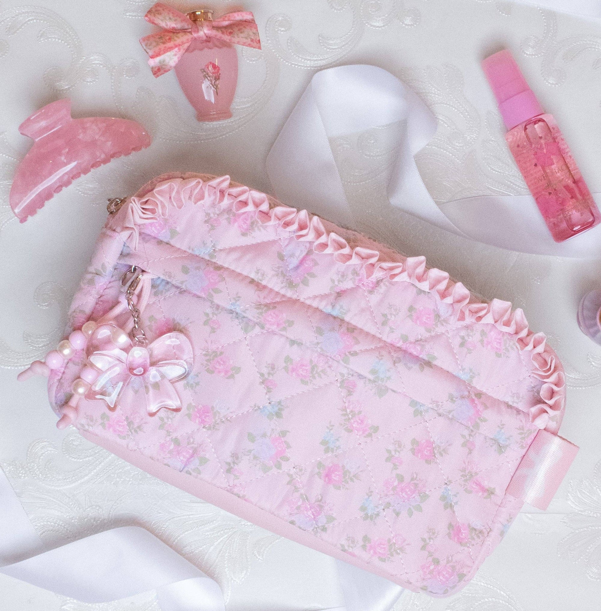 Pink cosmetic bag with decorative elements on a white fabric background