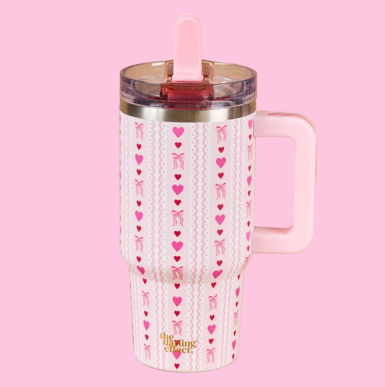 Pink tumbler with heart and bow pattern on a beige background