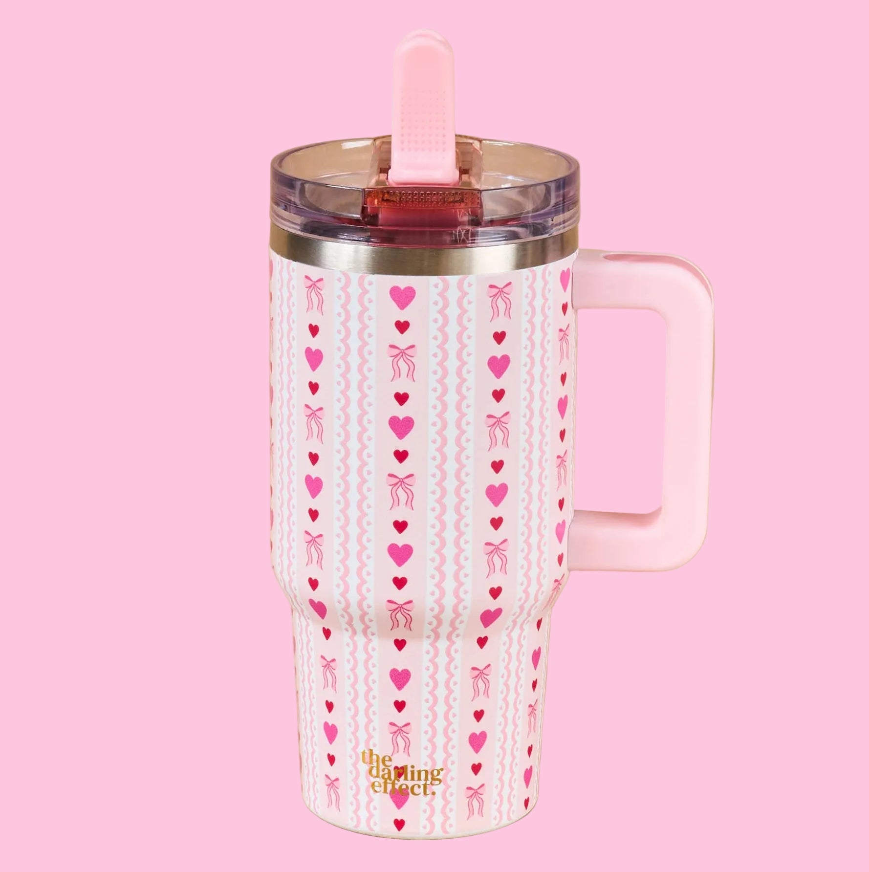 Pink tumbler with heart and bow pattern on a beige background