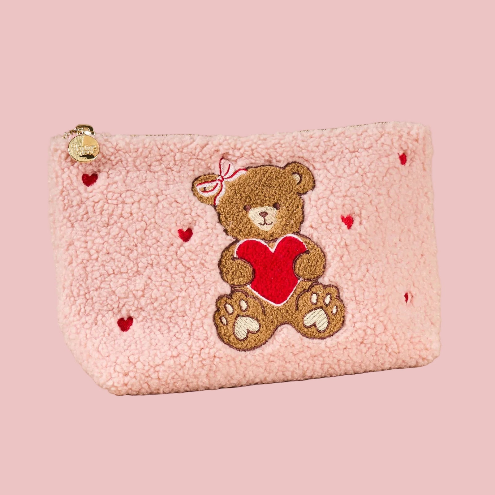 Pink pouch with teddy bear and heart design on a beige background
