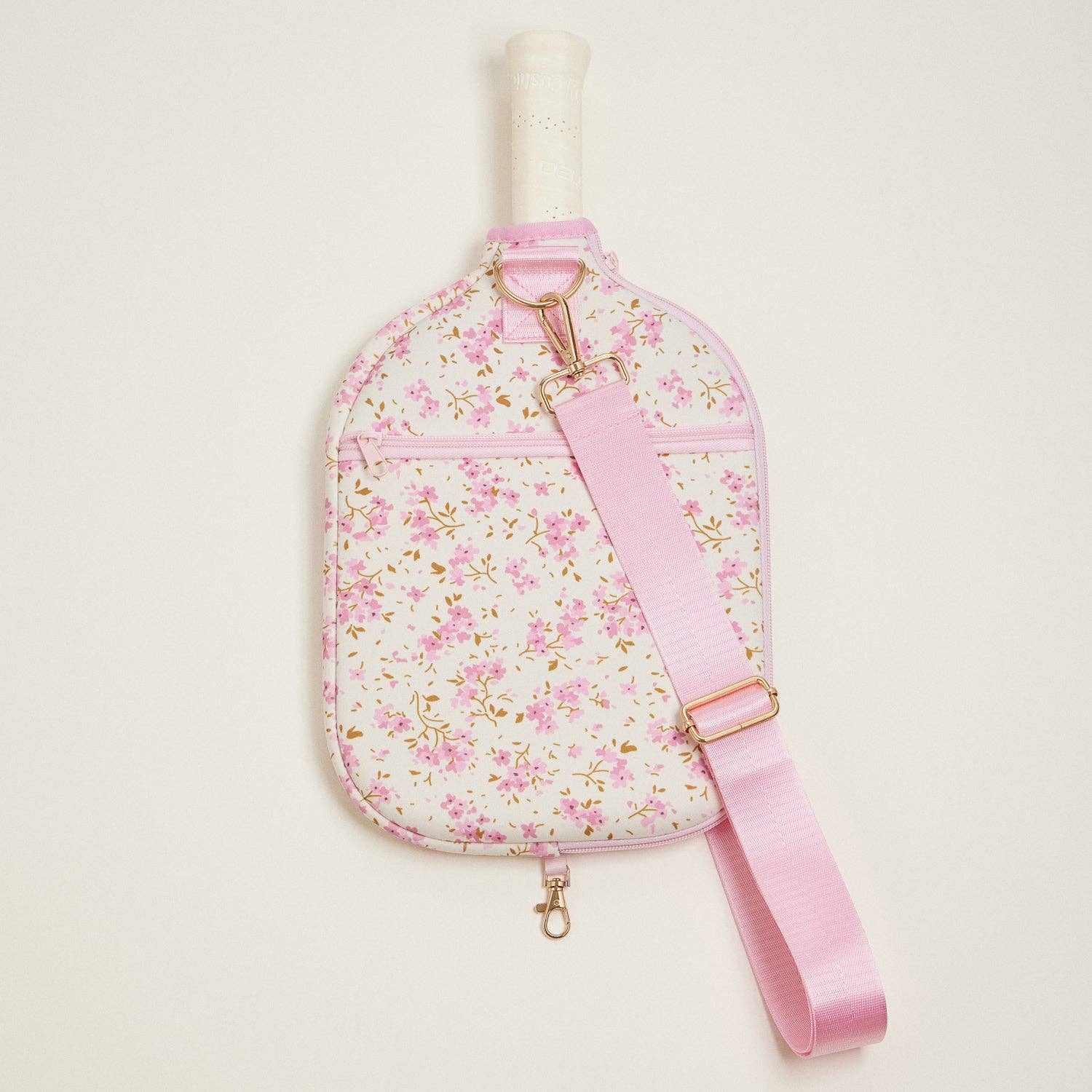 Floral-patterned bag with a pink strap on a light beige background
