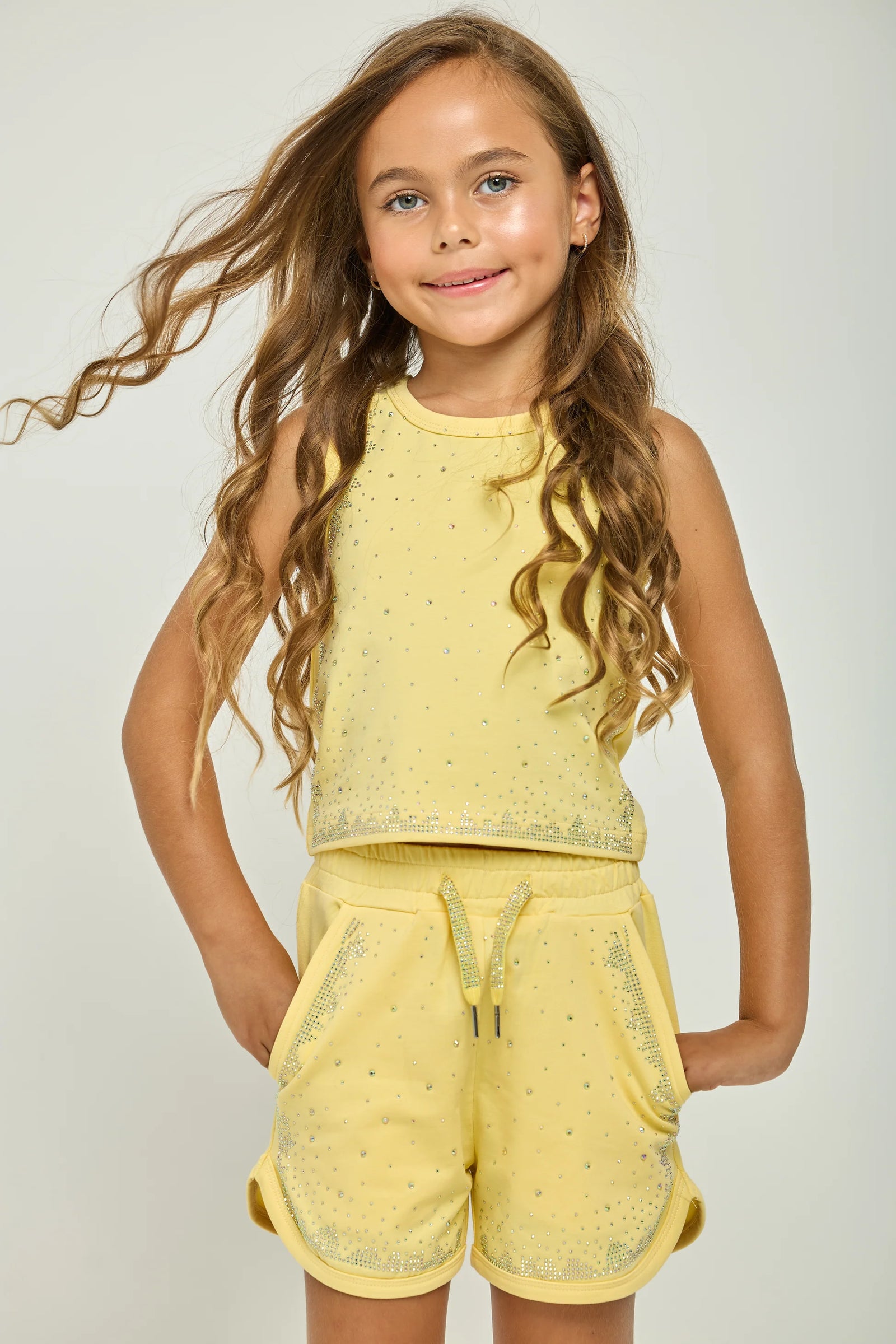 Young girl wearing a yellow outfit with a plain background