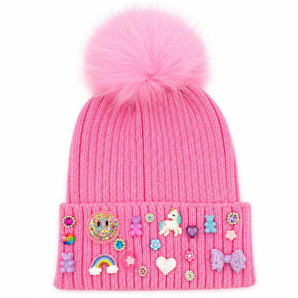 A bubblegum pink Bari Lynn knit winter hat with a large fluffy fur pom and a cuff embellished with colorful charms and sparkling jewel accents.