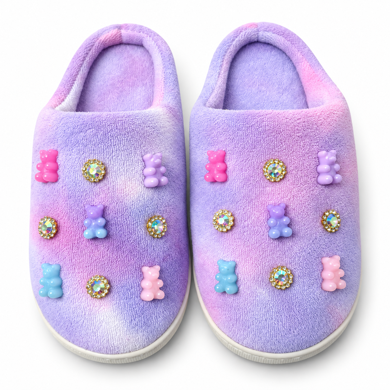 Pair of pastel lavender and pink plush girls slippers decorated with colorful gummy bear charms and sparkling iridescent jewel accents.