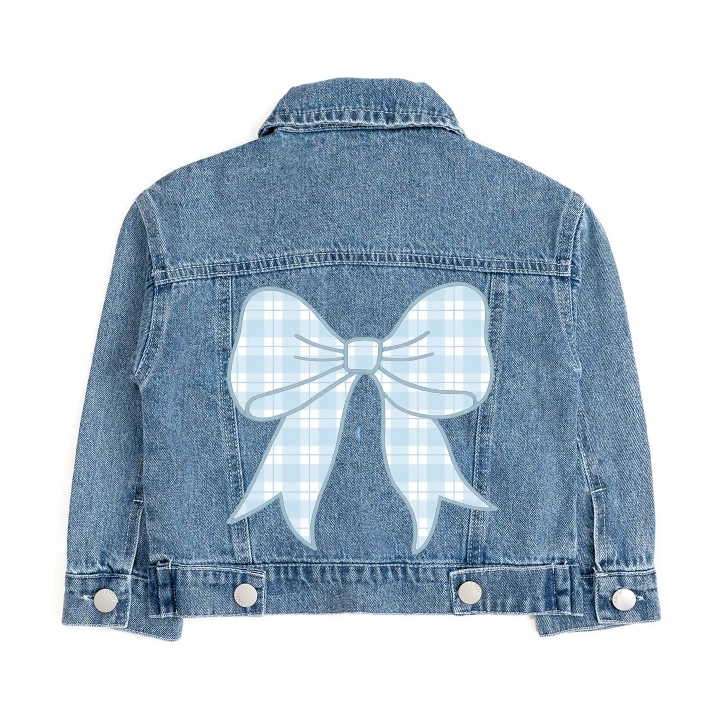 Tween girl wearing the Sweet Wink blue denim jacket with oversized pastel plaid bow patch layered over a blue dress.