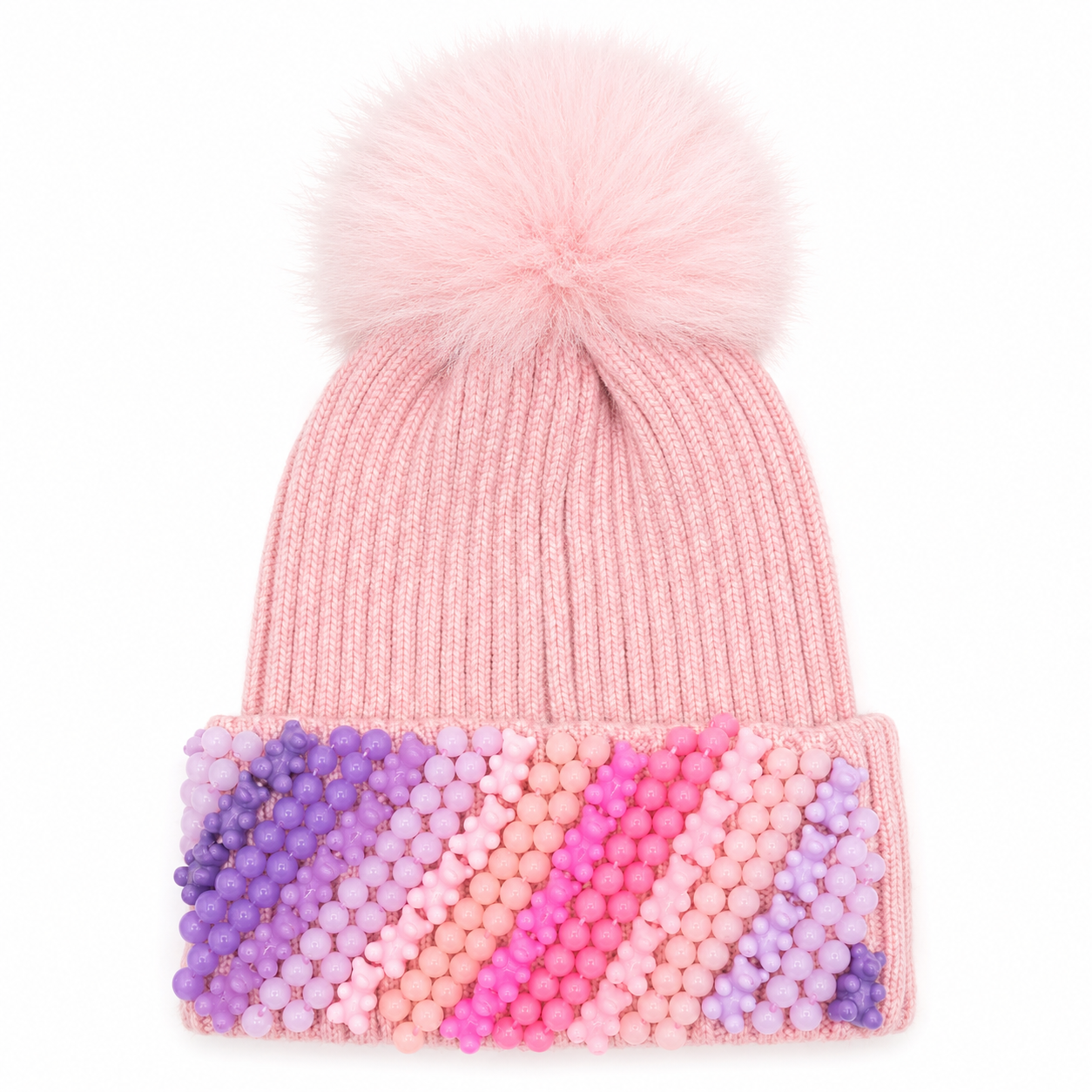 Pink ribbed knit winter hat for girls with a fluffy faux-fur pom and pastel gummy bear charm embellishments across the cuff, recommended for ages 3–10.