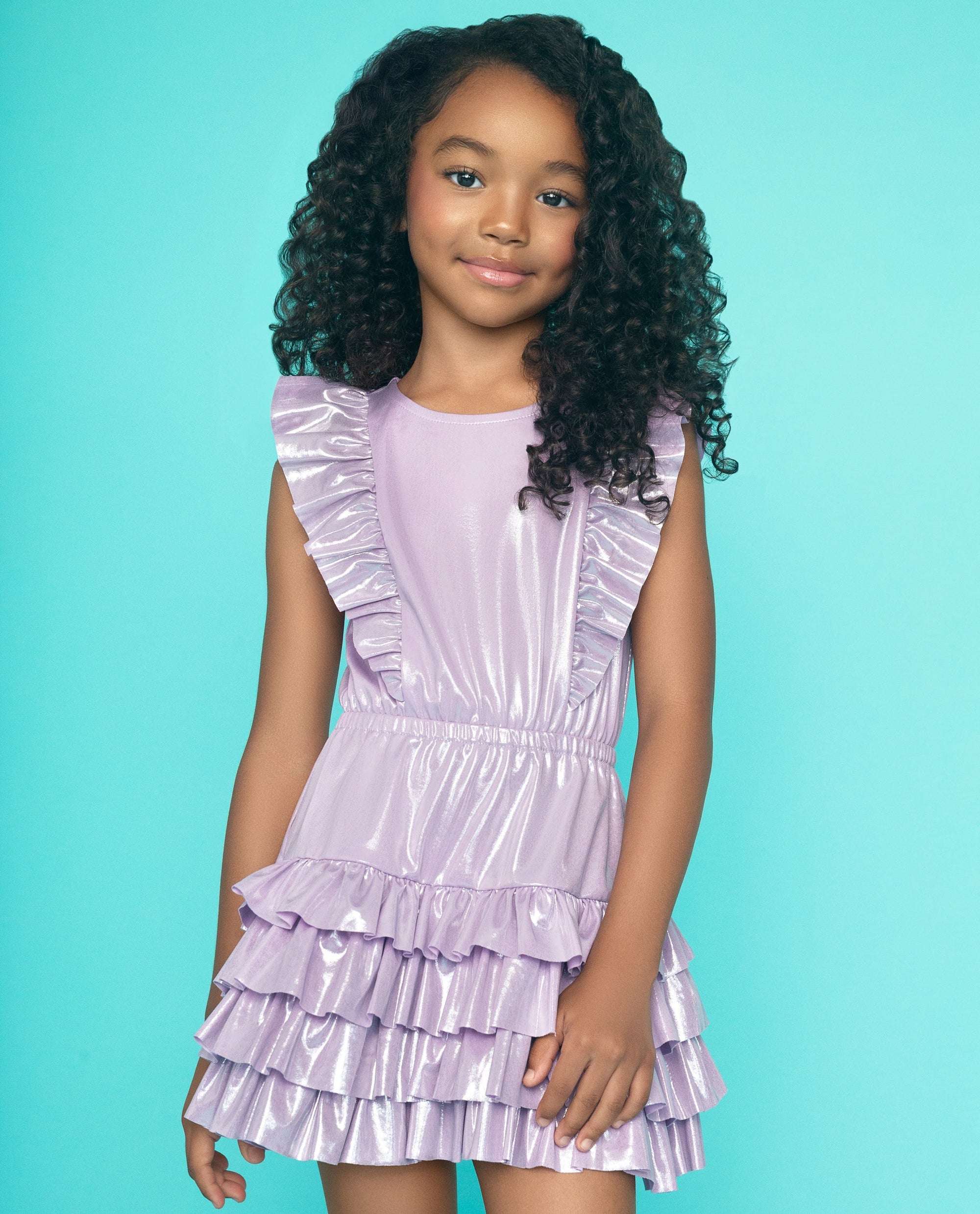 Young girl wearing a purple ruffled dress against a teal background