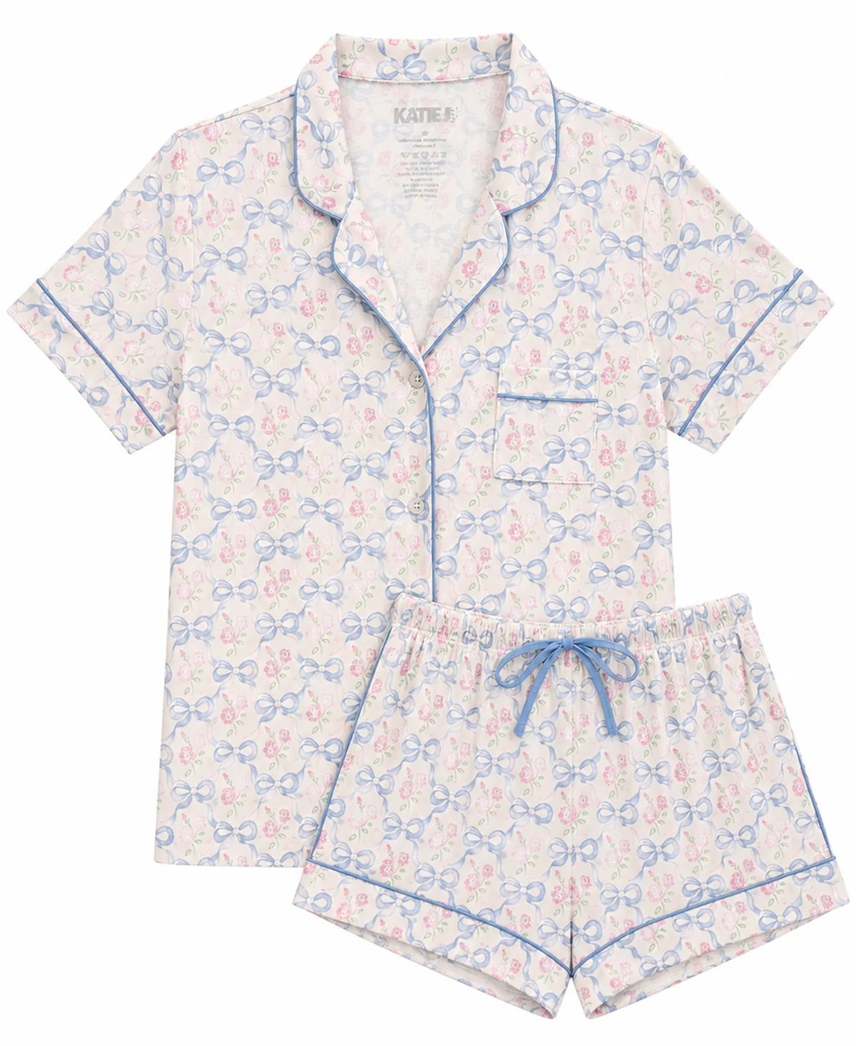 A two-piece girls pajama set featuring a short-sleeve button-front top and matching shorts. The pajamas have an allover repeating monogram-style pattern in light blue and pink on a white base, with light blue piping and a matching drawstring waist.
