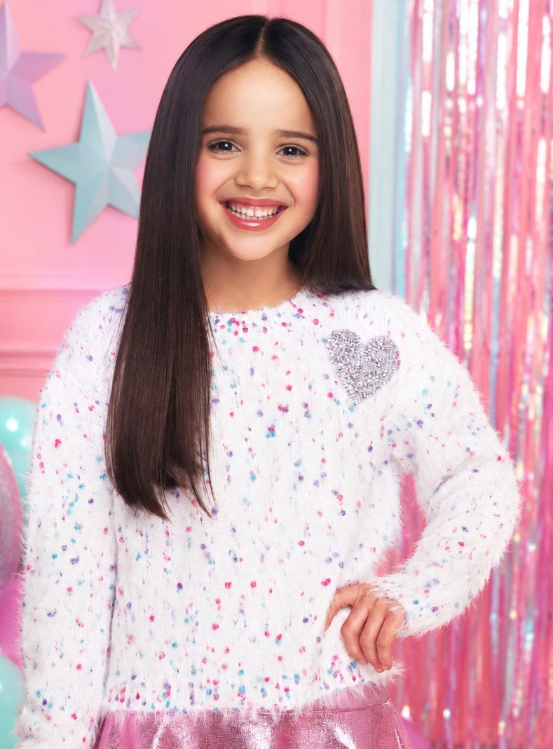 Little girl wearing a fuzzy white MIA New York sweater with colorful candy sprinkle details and a silver sequin heart.