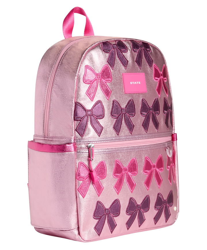 Angled view of the Metallic Bows Kane Backpack showcasing the spacious main compartment, front zip pocket, and premium metallic finish.