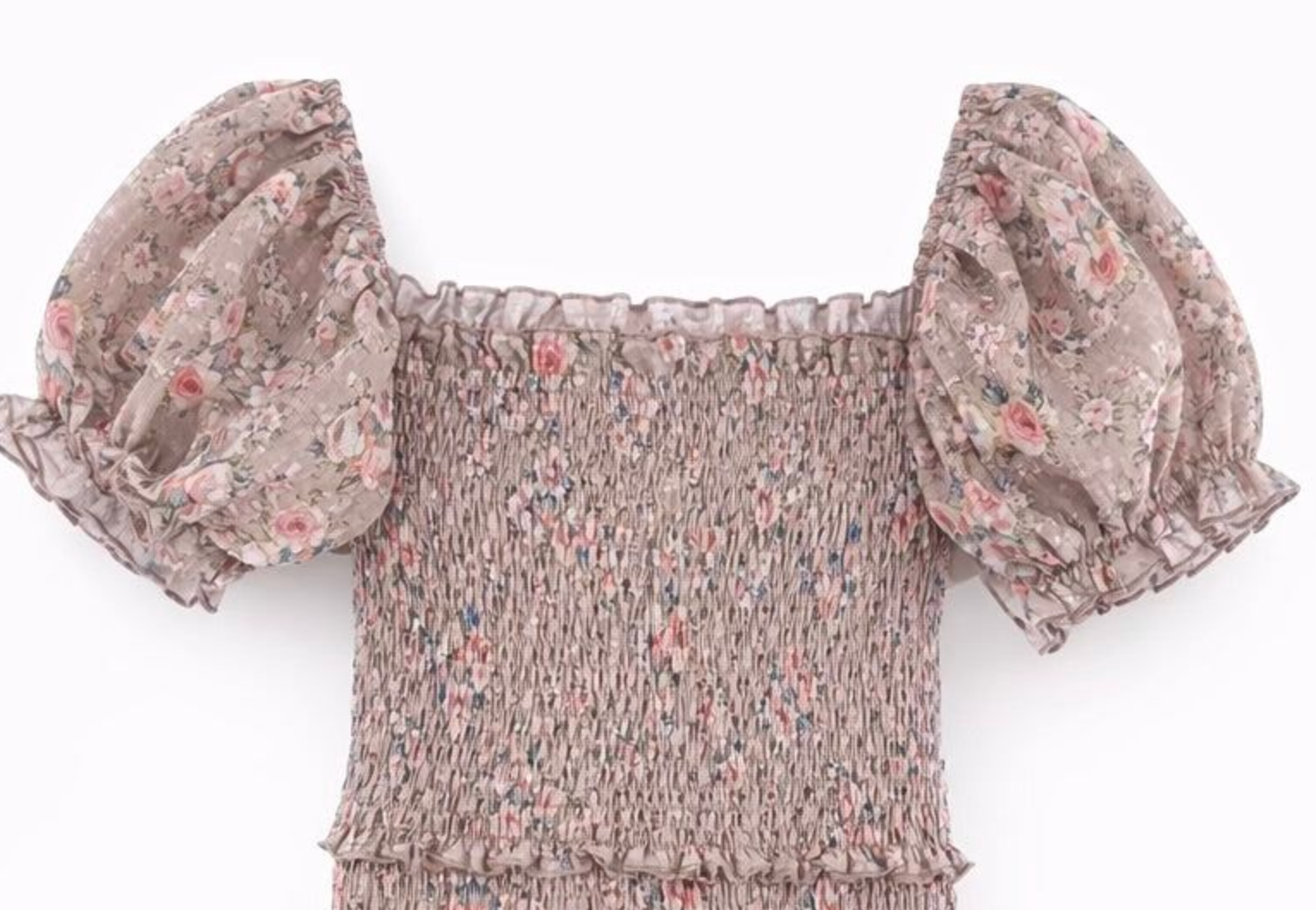 A close-up of a smocked blouse with puff sleeves, featuring a dusty pink and beige floral pattern on a white background.