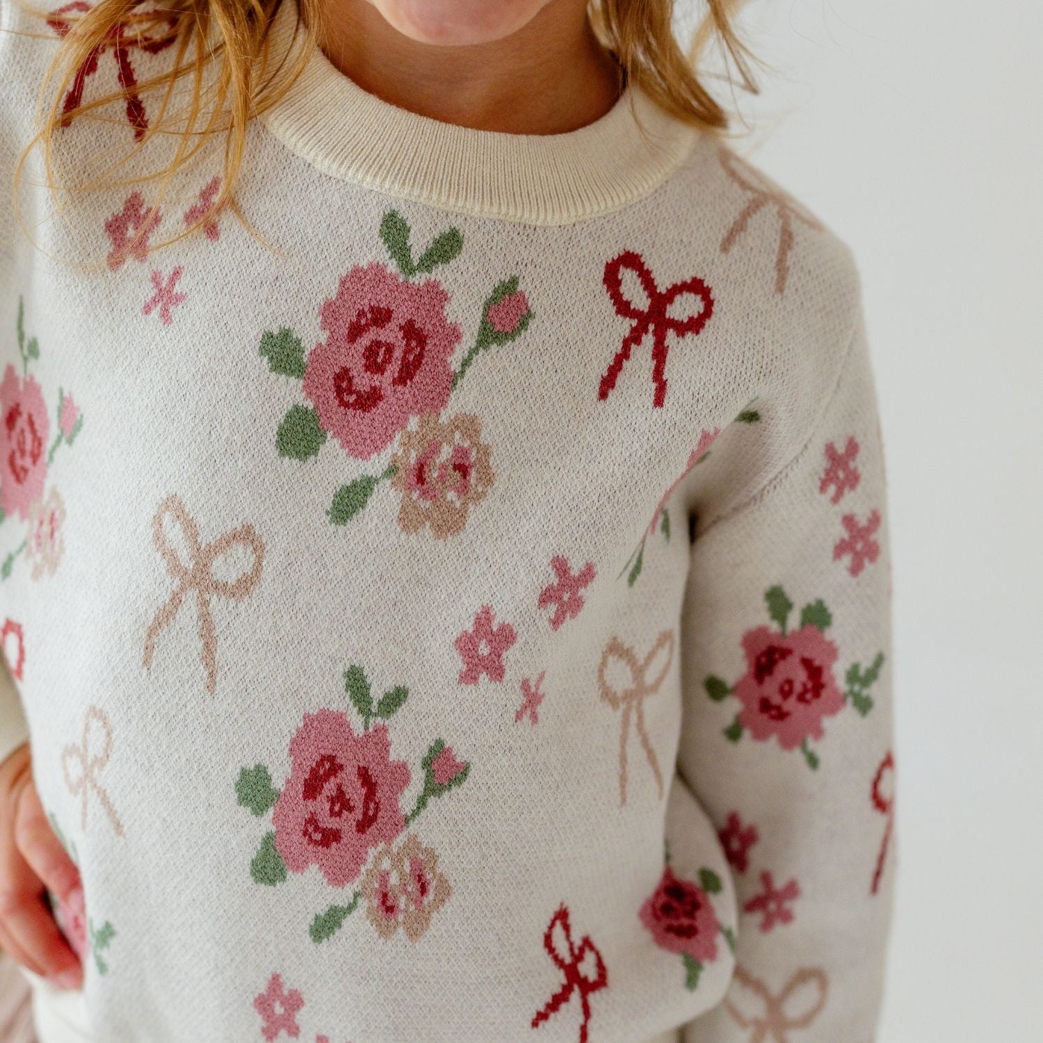 Girls Sweet Wink Coquette Rose Sweater featuring pink roses and coquette bow knit pattern on a cream sweater.
