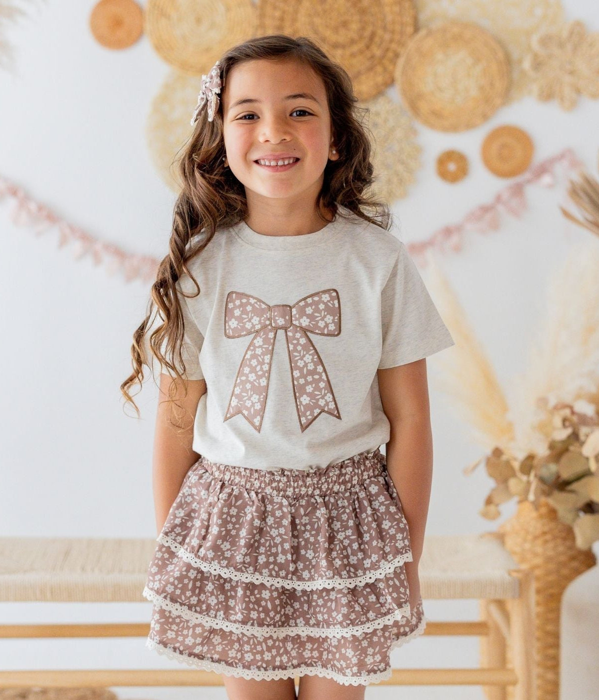 Close-up of the Sweet Wink girls floral bow graphic t-shirt featuring a coquette-inspired mocha bow appliqué.