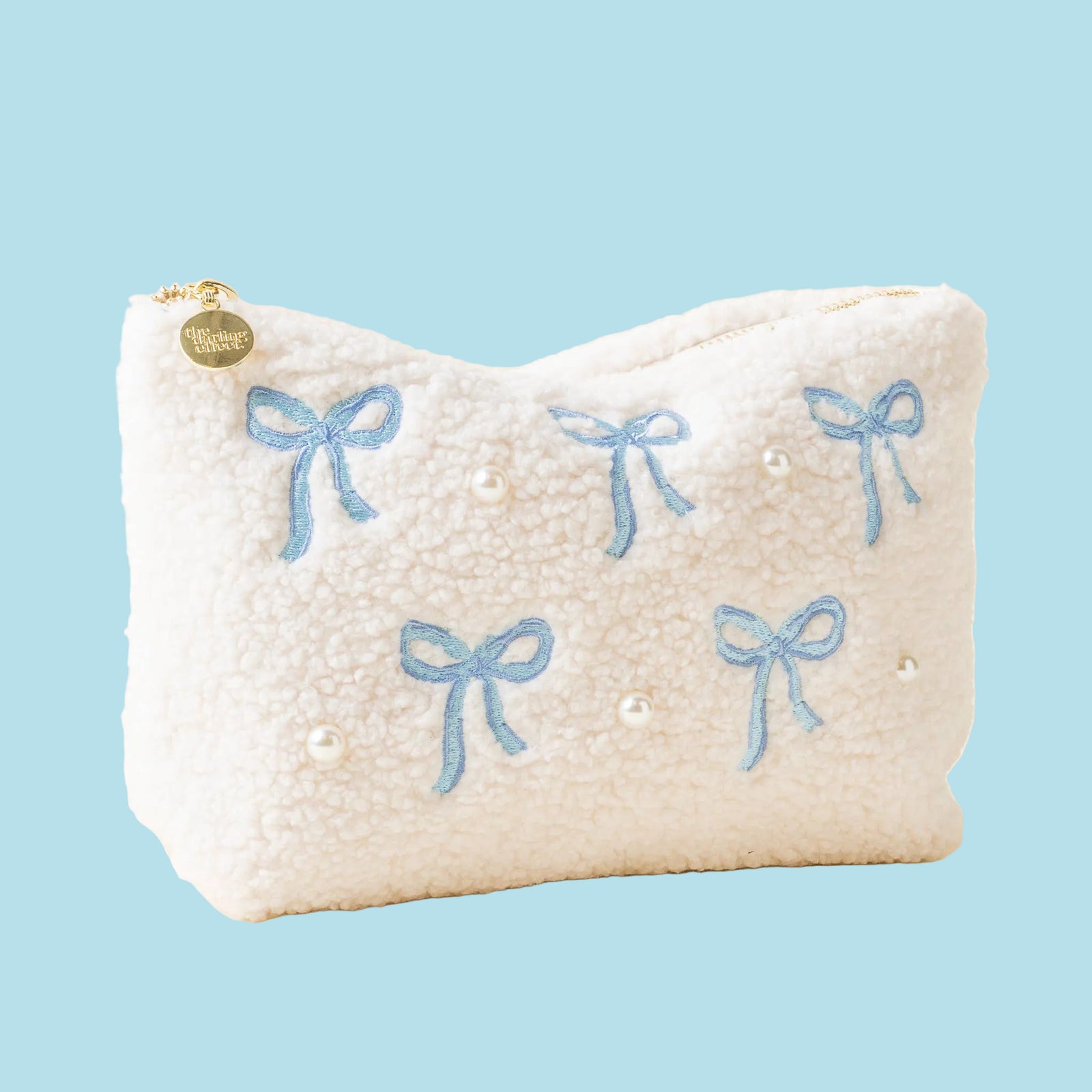 White pillow with blue bows and pearls on a light beige background