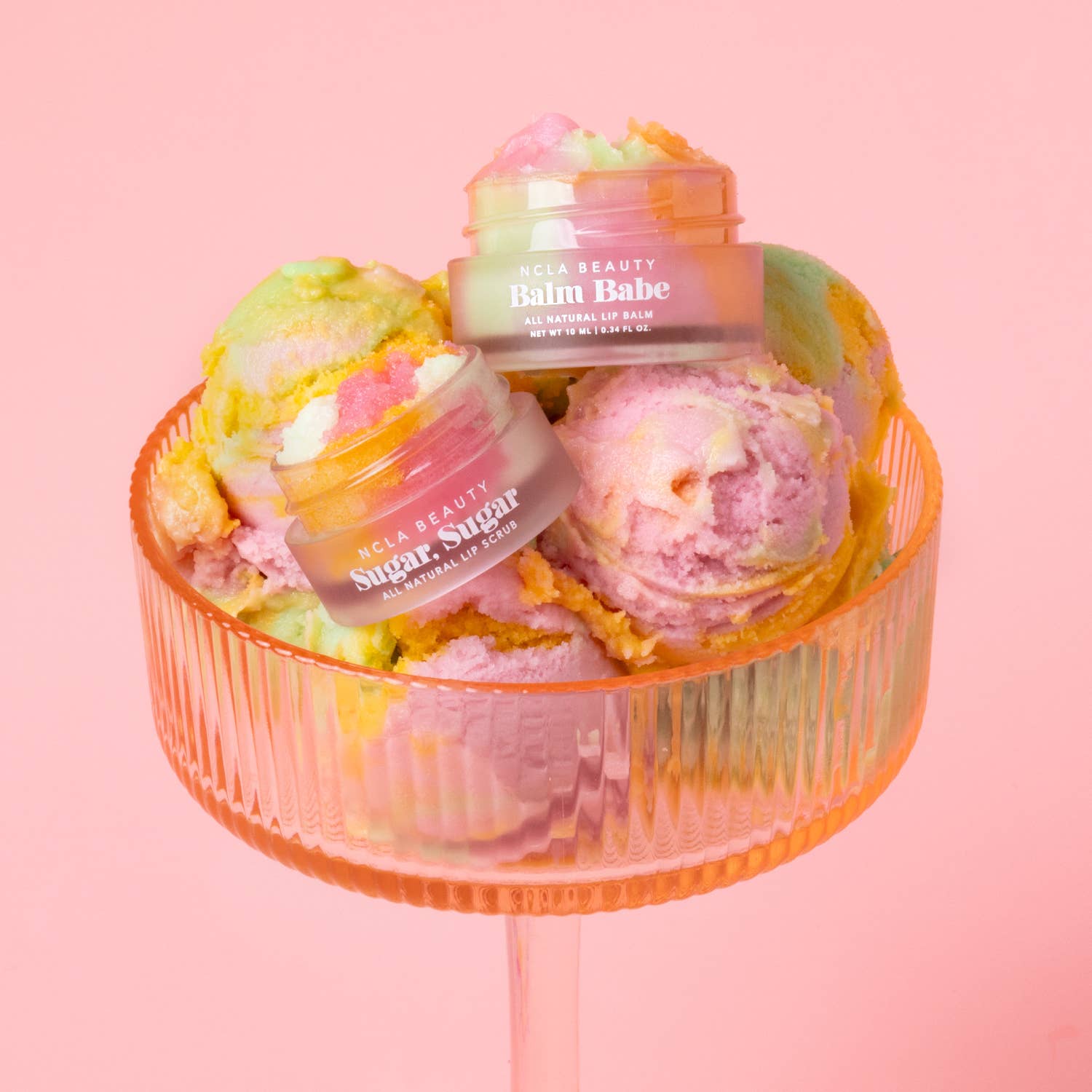 Balm Babe lip balm containers with colorful balm balls on a pink background