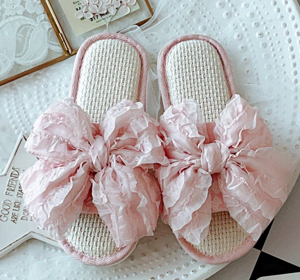 Pink slippers with floral bows on a white surface
