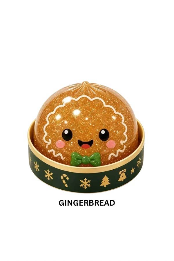 A round gingerbread-themed dumpling toy or container with a smiling face, shown on a plain white background. The top is golden brown with white icing-style lines, black eyes, pink cheeks, and a small green bow tie.