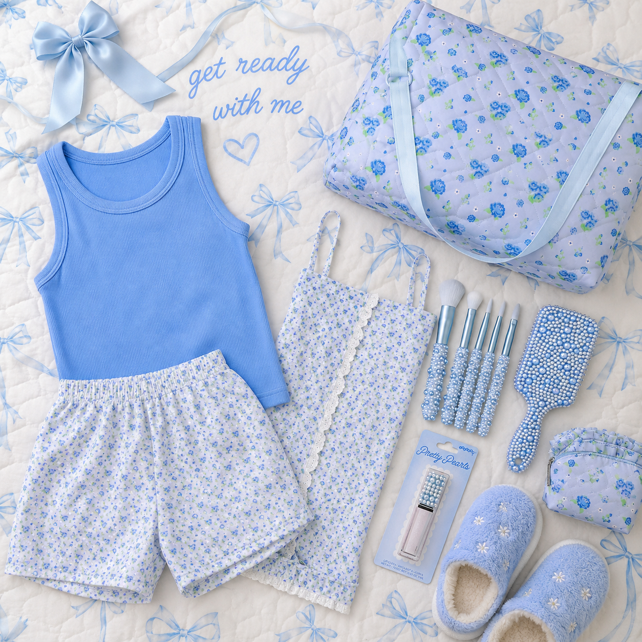 A coordinated girs outfit and accessory gift set arranged on a quilted cream bedding surface. The set includes a light blue tank top, matching floral shorts, a floral camisole, a floral tote bag, a blue satin bow, a small blue pouch, a brush, a mirror, a lip product, and blue slippers.