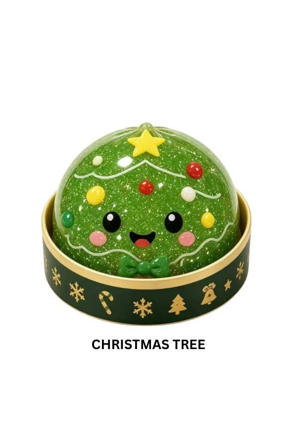 A green glittery Christmas tree smystery holiday dumpling squishy with a cute face, decorated with colorful ornaments and a yellow star, sitting in a gold-rimmed dark green base with gold holiday icons. The text 'CHRISTMAS TREE' is printed below on a white background.