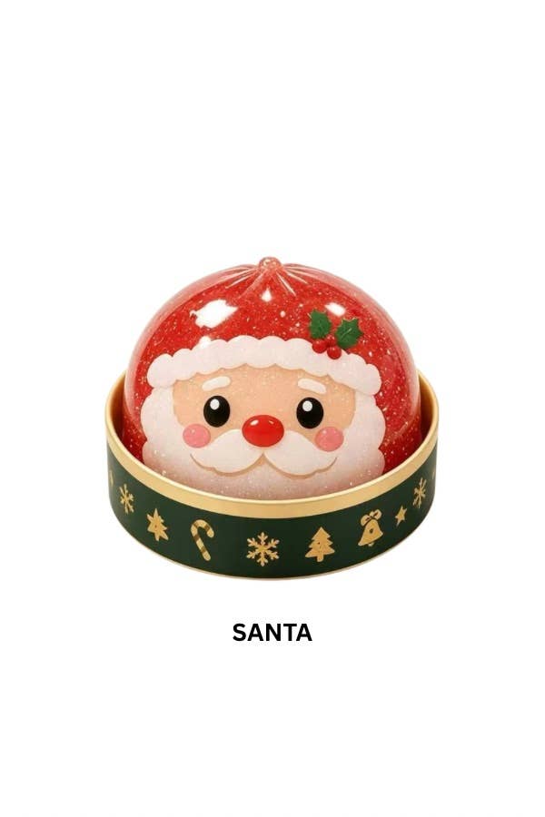A Santa-themed mystery holiday dumpling squishy featuring a red glittery dome with a printed Santa face, sitting in a gold-rimmed base with a dark green band decorated with gold holiday motifs. The word 'SANTA' appears below on a white background.