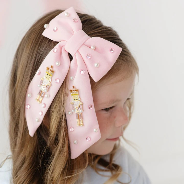 Girl wearing a pink nutcracker Christmas gemstone bow hair clip